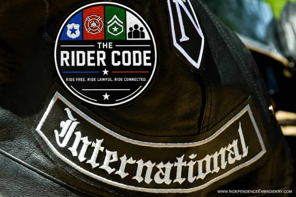 The Rider Code patch on a leather motorcycle vest above an International rocker, representing lawful riders united under one code.