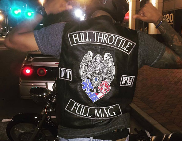 FTFM rider at night with arms raised, vest with patches